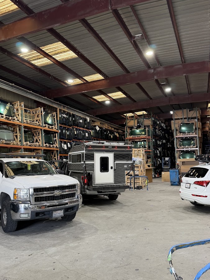 Inside the shop: racks of replacement windshields, a service truck and customer vehicles